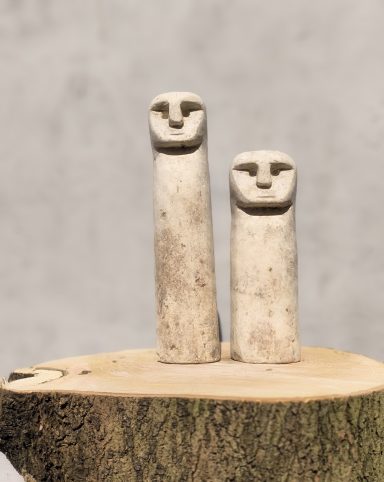 Twee abstracte stenen figuren op een houten stomp.